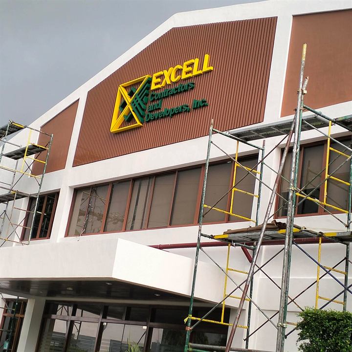 Gold acrylic letters on a building facade being finished under scaffolding