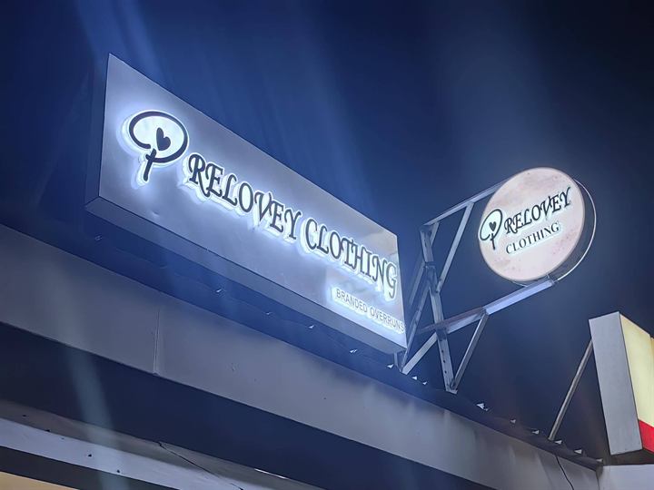 Relovey Clothing lit acrylic letters and round sign at night